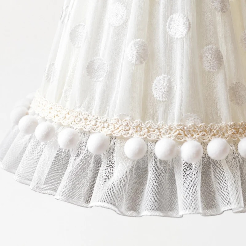 Close detail of the lace trim, dotted mesh and pom pom edge
