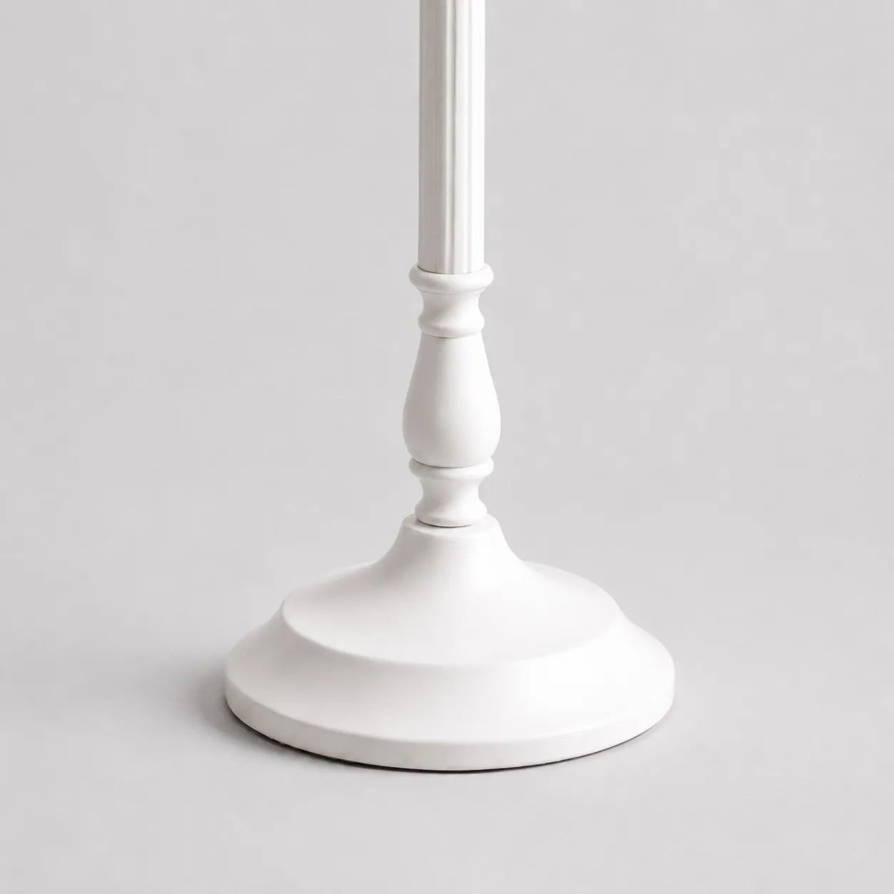 Close-up of sculpted white metal stem and smooth round lamp base